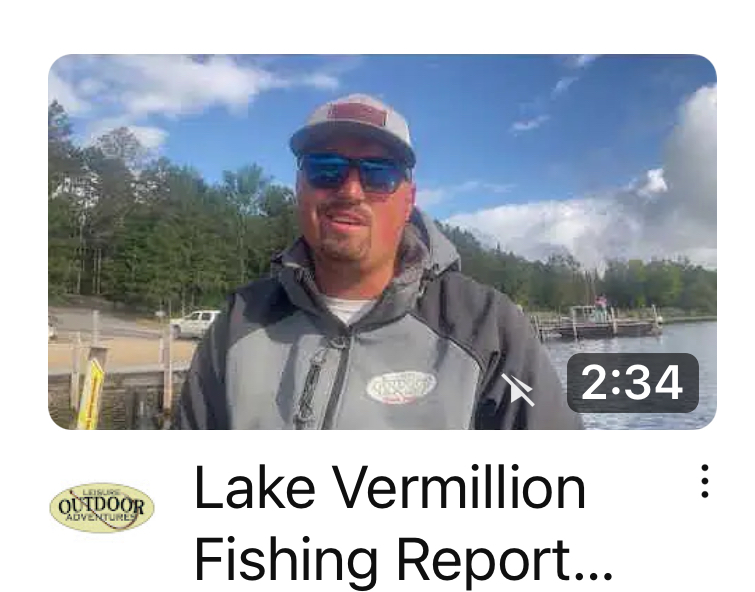 A man wearing sunglasses, a cap, and a hooded jacket is standing in front of Lake Vermillion with trees in the background. The text on the image reads 