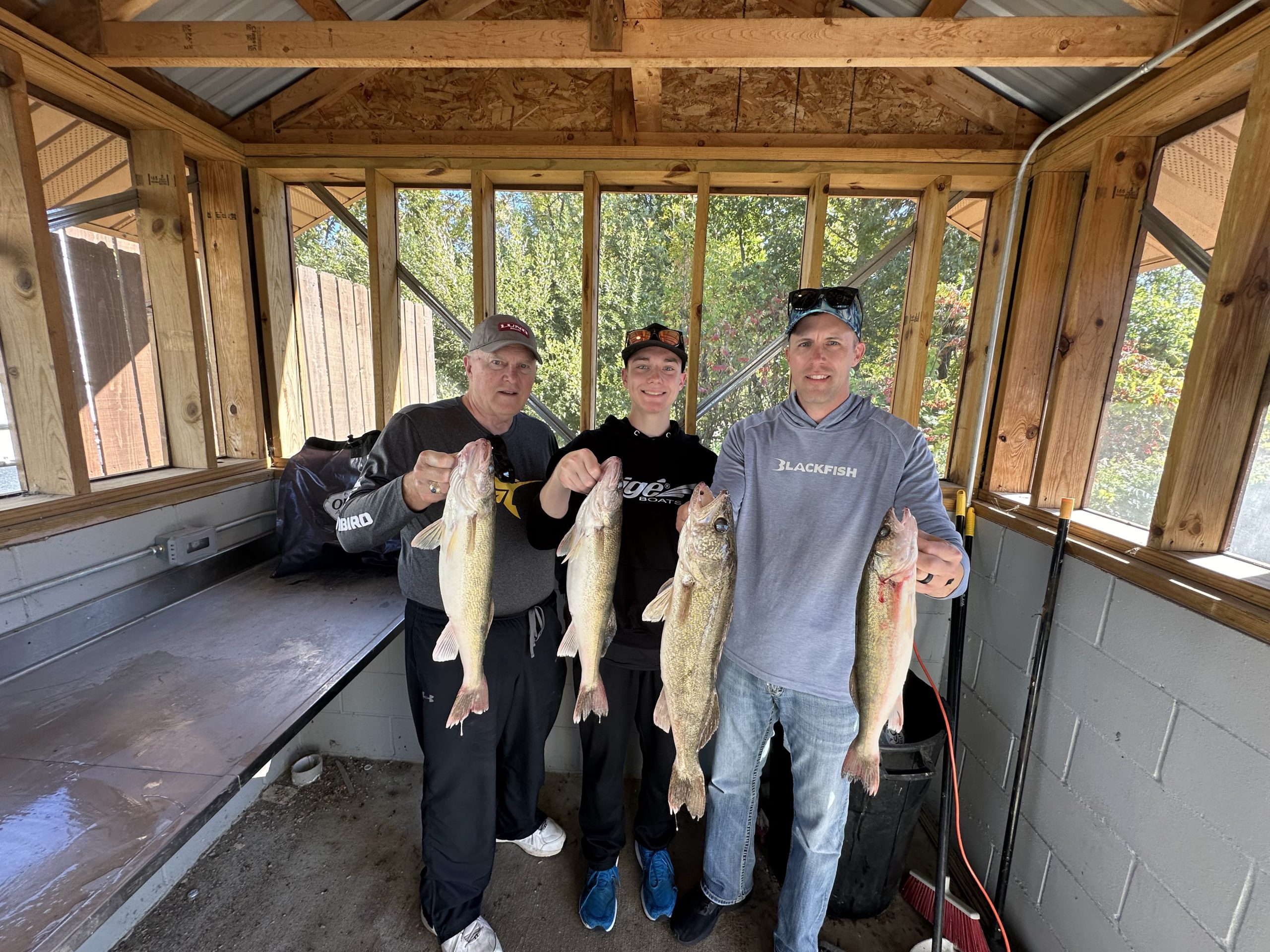 Three people are standing in a wooden shed, each holding up two fish. They appear to be proud of their catch. The shed has windows all around, letting in natural light, and some trees are visible outside. It's almost as if the scene was created through auto draft perfection. - Leisure Outdoor Adventures - Fishing Guide Services in Northern Minnesota Three people are standing in a wooden shed, each holding up two fish. They appear to be proud of their catch. The shed has windows all around, letting in natural light, and some trees are visible outside. It's almost as if the scene was created through auto draft perfection.
