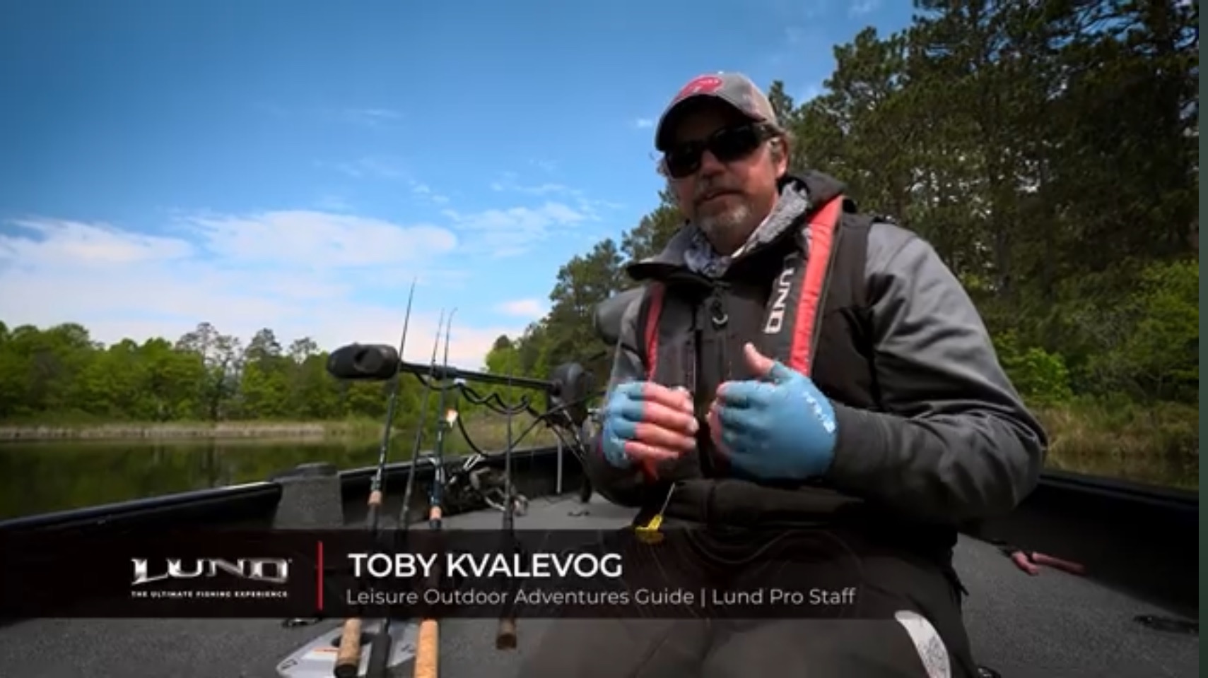 A man wearing sunglasses, a cap, and a life vest sits in a boat with fishing gear on a calm lake, surrounded by trees under a partly cloudy sky. Text reads: “TOBY KVALEVOG, fishing guide, Leisure Outdoor Adventures Guide, Lund Pro Staff.”.